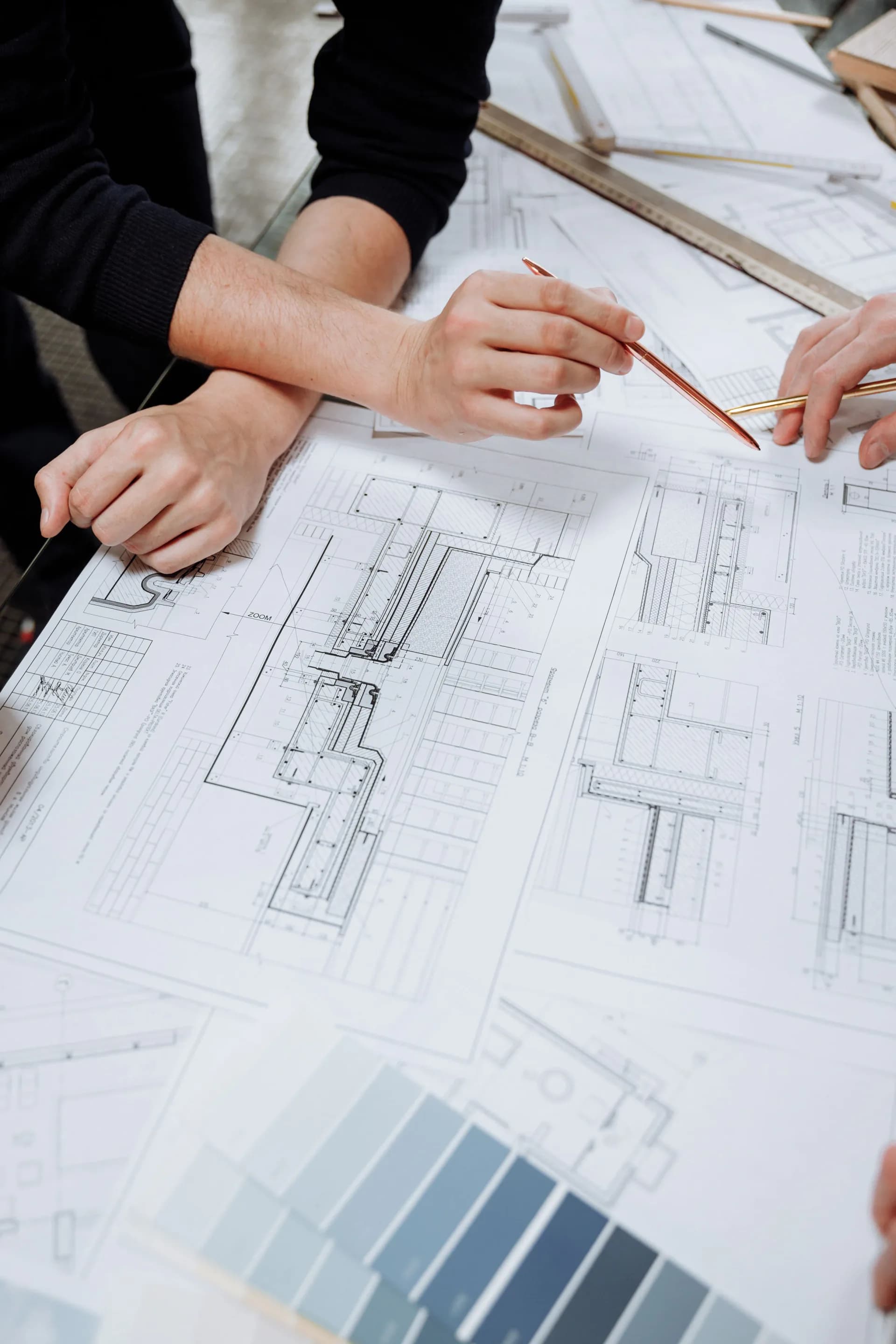Two people leaning over large-format technical drawings spread across a table, discussing them.
